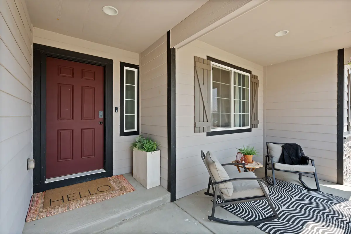 A covered porch with a poured concrete floor and painted support posts