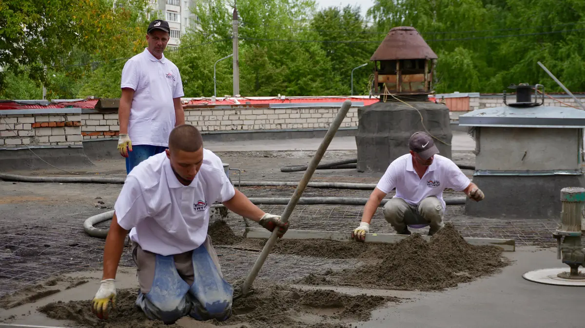 A crew hand-screeding freshly placed concrete across a slab