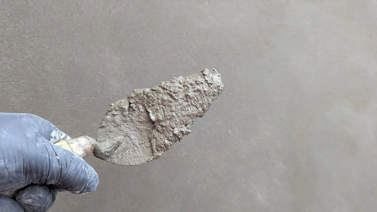 A trowel loaded with resurfacing mix held against a concrete surface